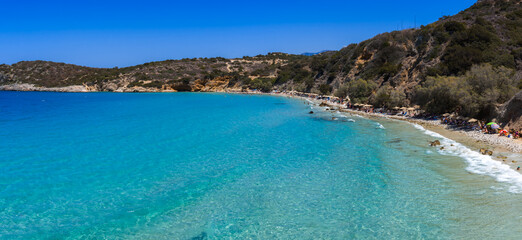 Aerial view of Voulisma Beach in Crete, Greece, showing turquoise waters, sandy shoreline, shrub...