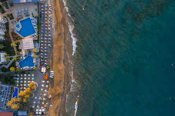 Aerial view of Stalida, Crete, showing a sandy beach with sun loungers, turquoise waters, resort...