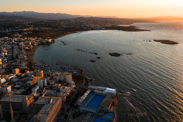 Aerial view of Chania town on Crete during sunset, featuring a curved coastline, shimmering bay,...