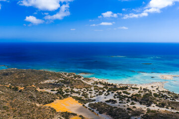 Aerial view of Elafonisi Beach in Crete, Greece, showing turquoise and deep blue waters, pinkish...