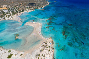 Aerial view of Elafonisi Beach in Crete, Greece, showing turquoise and deep blue waters, coral...