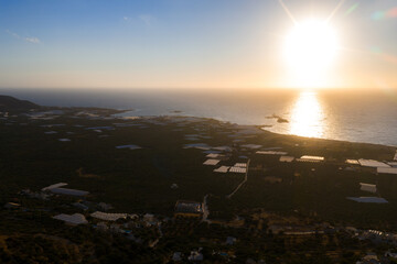 Aerial view of Crete, Greece, at sunset showing agricultural fields, greenhouses, olive groves,...