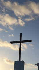 Imagem da cruz em frente &agrave; capela em Fernando de Noronha, destacando arquitetura hist&oacute;rica, c&eacute;u azul, luz do dia e o cen&aacute;rio tropical da ilha paradis&iacute;aca