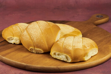 Colorful freshly baked homemade bread rolls on a wooden board with copy space in the foreground