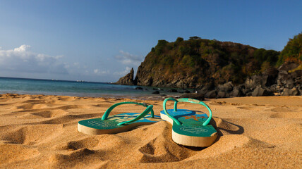 Chinelo deixado na areia de uma praia de Fernando de Noronha, simbolizando descanso, viagem e clima tropical paradis&iacute;aco