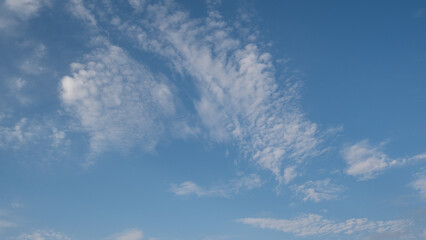 Blue sky with scattered white cirrus clouds. The clouds vary in size and shape, creating a serene atmosphere. Background light blue