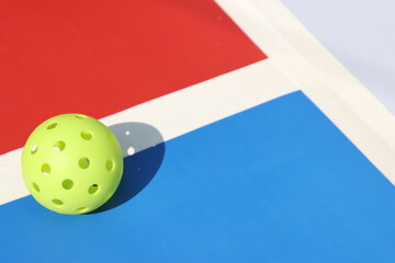 Pickleball ball in a court floor with vibrant color
