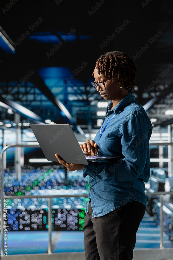 Poster portrait of black engineer working on data center industrial platform, completing software updates a