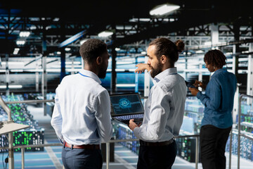 Software developers monitoring neural network on industrial platform, using devices for LLM visualization. Server hub engineering team overseeing machine learning processing on database.