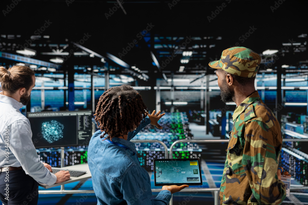 Poster army operators in server hub using device to run drone control software, looking at mission map over