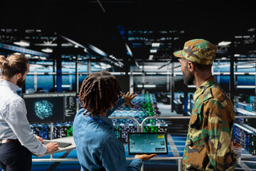 Army operators in server hub using device to run drone control software, looking at mission map overlay via satellite imagery. Diverse military experts develop national defense strategy.