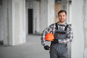 Construction worker holding helmet in building under construction