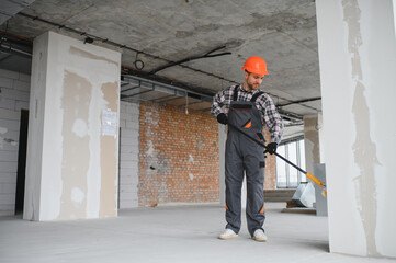 Construction worker painting wall with roller in building under construction