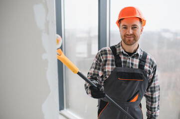 Construction worker painting wall with roller in building under construction