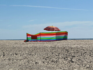bunter Windschutz und Sonnenschirm am Strand