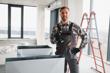 Hvac technician installing ventilation system in building under construction