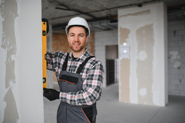Construction worker using spirit level ensuring vertical alignment on building site