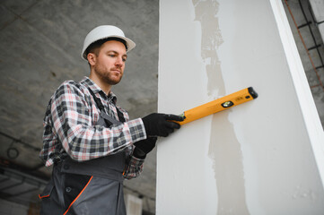 Construction worker checking wall straightness with spirit level
