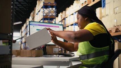 Black woman placing adhesive shipment tags on cardboard boxes, handles labeling and packaging tasks...