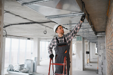 Construction worker installing ventilation system in building