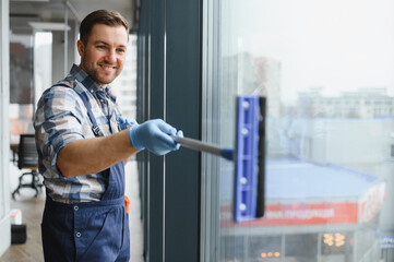 Professional cleaning service worker washing windows in office building