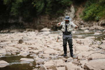 Fisherman casting line in river, trout fishing adventure