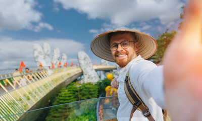 Happy Young caucasian male tourist taking selfie on golden bridge in ba na hills, Da nang, Vietnam trip