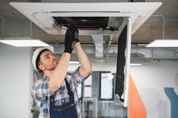 Electrician installing air conditioning system on ceiling