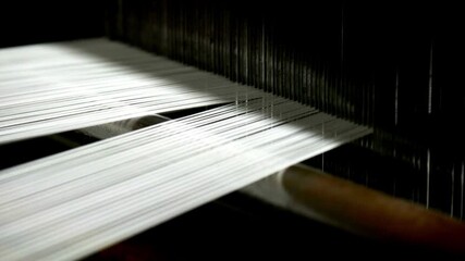 Weaving loom at a textile factory, closeup. industrial fabric production line Spinning factory, production of fabrics, thread of silk, linen, and synthetics