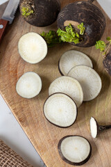 Sliced black radish on wooden cutting board.