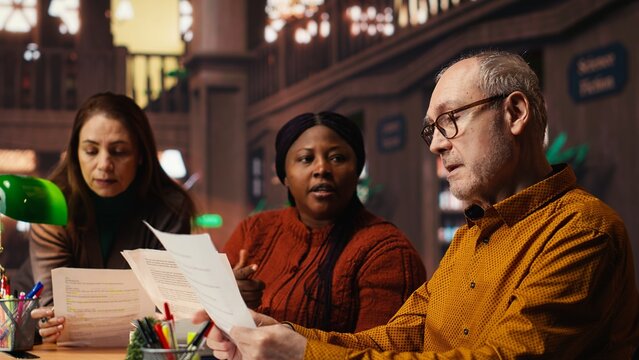 Diverse actors team reading their scripts during theatre drama play rehearsal in library, showing dedication to script practice. Role preparation together for dramatic arts reenactment.