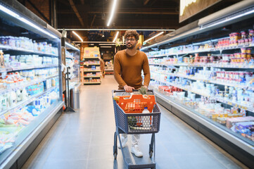 Customer pushing shopping cart in supermarket buying groceries
