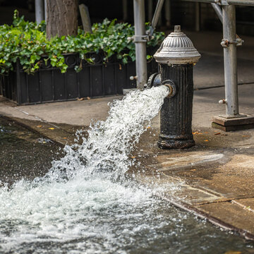 Open fire hydrant in the summer spewing water onto the street