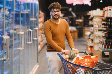 Arab man pushing shopping cart in supermarket buying groceries