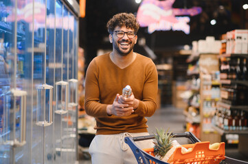 Smiling arab man choosing water bottle in supermarket