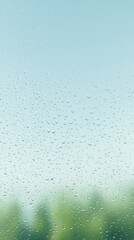 Raindrops on glass creating a soft blurred view of greenery outside in the morning