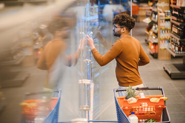 Customer opening refrigerator door in supermarket, choosing groceries, healthy food, shopping...