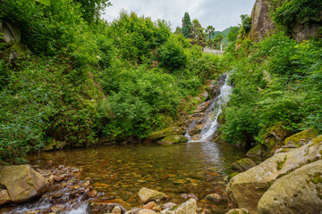 picturesque waterfall cascading over rocks into a crystal-clear pool, surrounded by lush greenery...