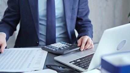 Businessman analyzing financial data on laptop and calculator. Close-up of a professional auditor...