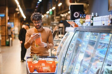 Customer reading product information while shopping in supermarket