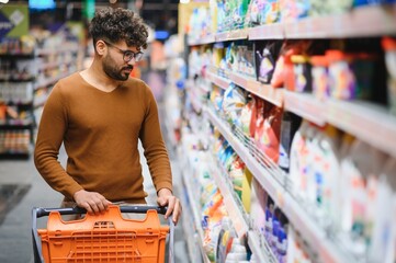 Arab man choosing groceries walking with shopping cart in supermarket