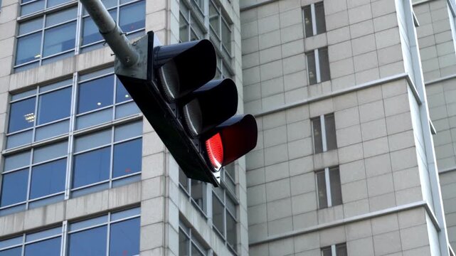 Red traffic light illuminating the morning city, creating a striking visual contrast. Blinking traffic light, signifying caution and drawing attention.