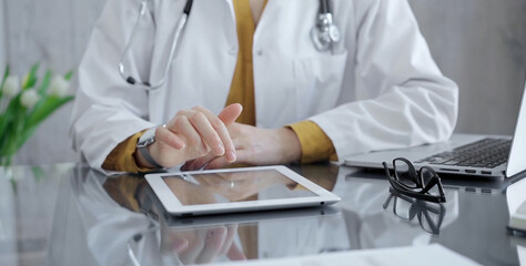 Doctor woman using tablet on the glass desk in medical office. Medicine and health care