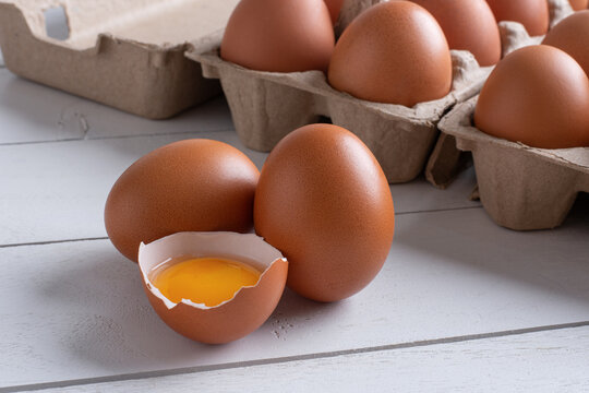 fresh raw chicken eggs with broken egg shell showing egg yolk