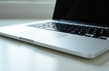 Close-up of a modern laptop with a sleek silver body and black keyboard on a white surface