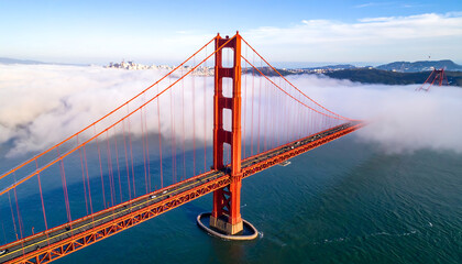Golden Gate Bridge Aerial View: Majestic Structure Emerging from Fog, San Francisco Skyline in Background, Dramatic Lighting, Serene Mood.