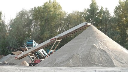 Maszyna przesiewająca piasek z widocznym taśmociągiem, który usypuje górę piasku