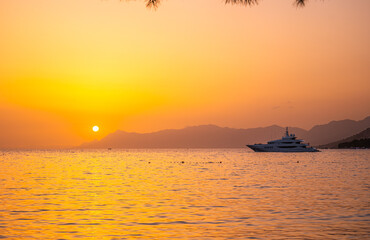 Luxury yacht on Adriatic Sea at sunset in Makarska Croatia with golden orange sky, calm water...