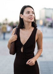 Slender female brunette walks in vicinity of Passeig Nou in Barceloneta, spends time in motion,...