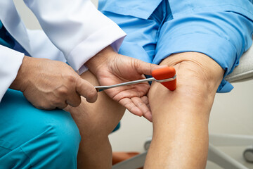 Asian doctor use hammer knock senior woman patient to check knee reflex, nerve and muscle in hospital.